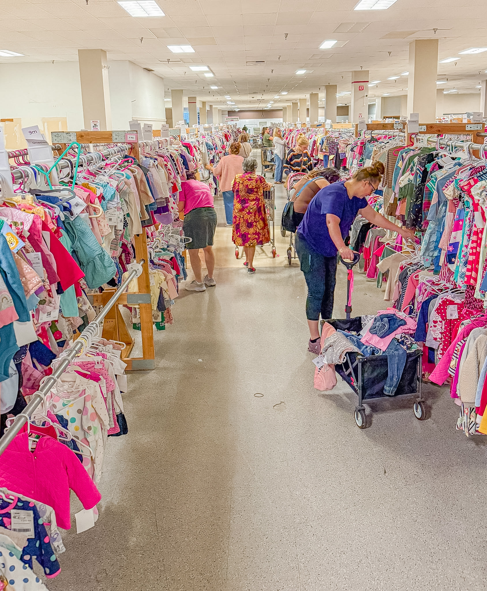 High view of an aisle of girls clothing with lots of shoppers filling their wagons and carts