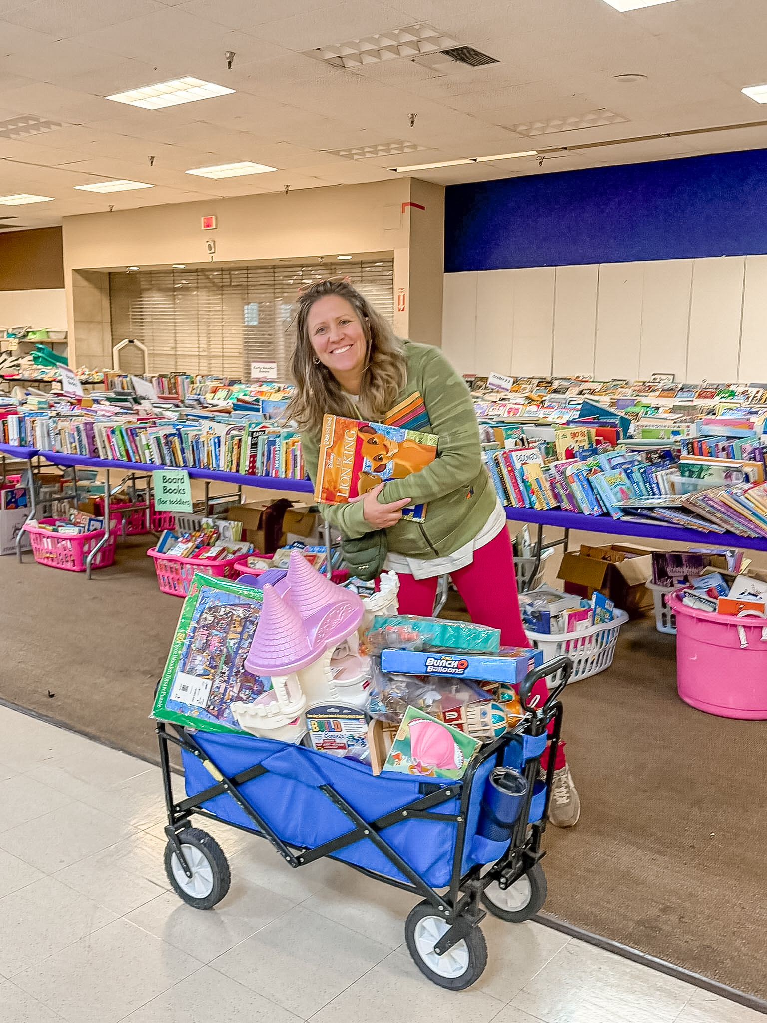 Shopper leaning over her full wagon with a big smile holding a toy