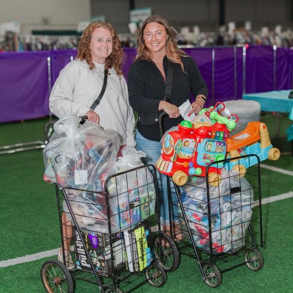 two smiling women with carts full of clothing and toys