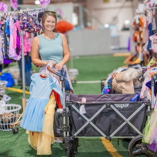 one smiling woman with a wagon and several dresses on hangers
