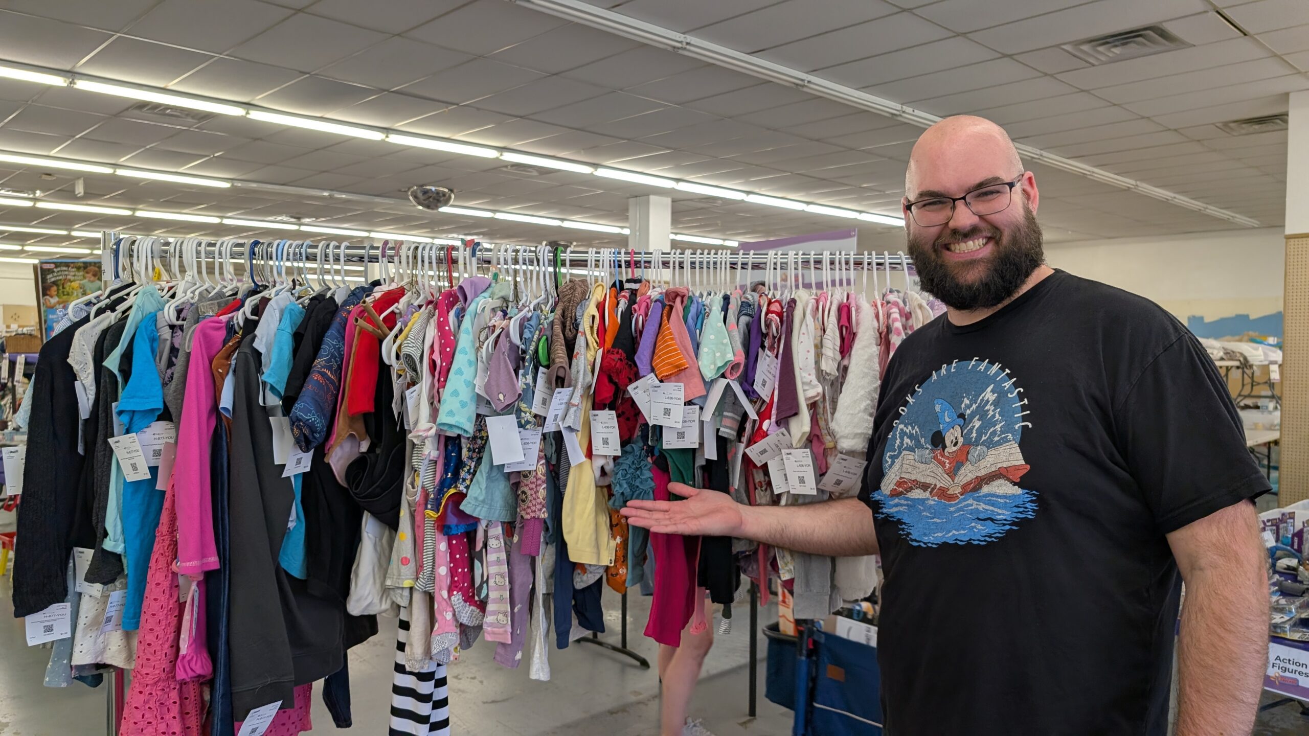 Man gesturing to full clothing rack