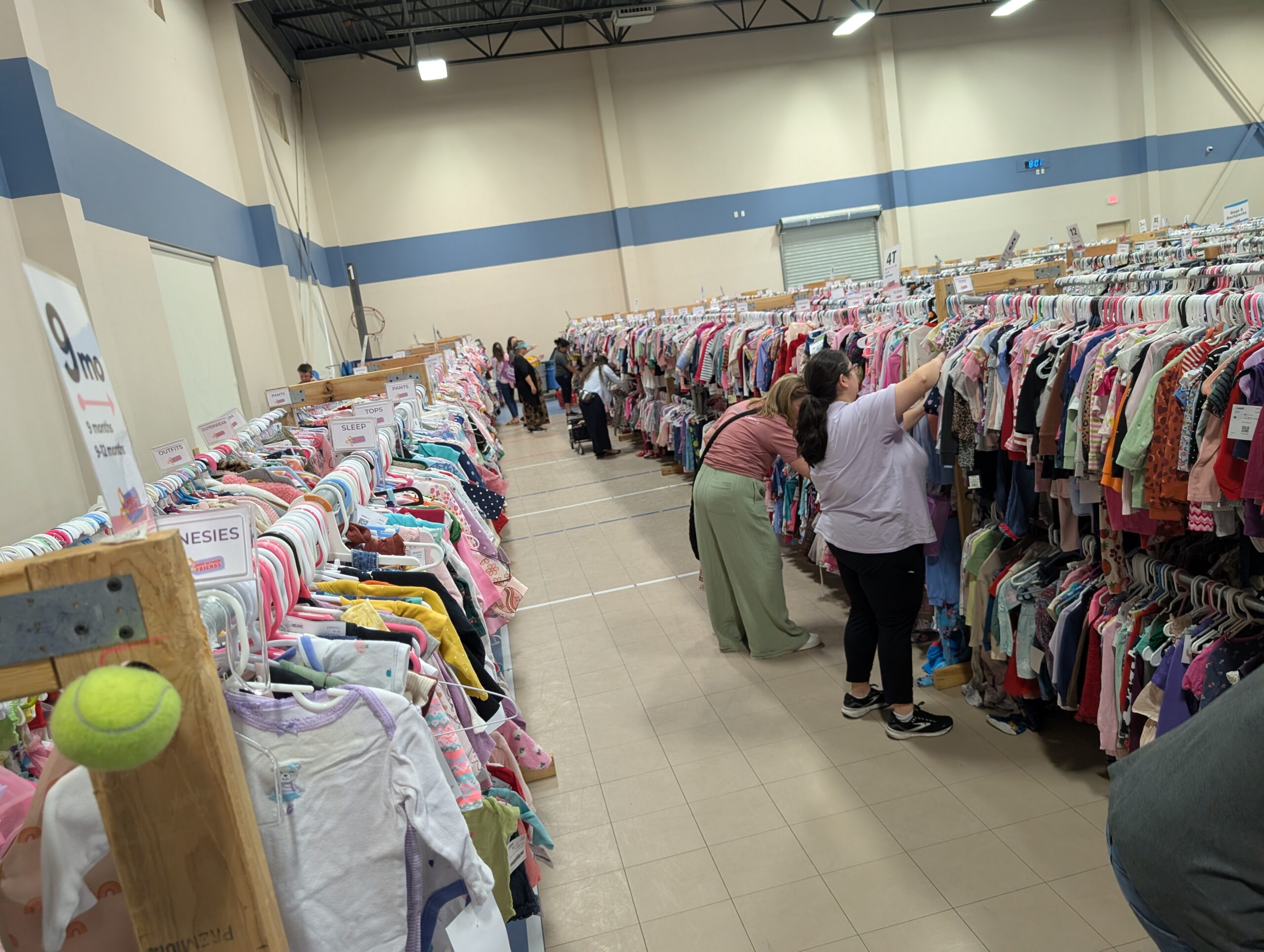 Shoppers in a row of clothing stretching into distance
